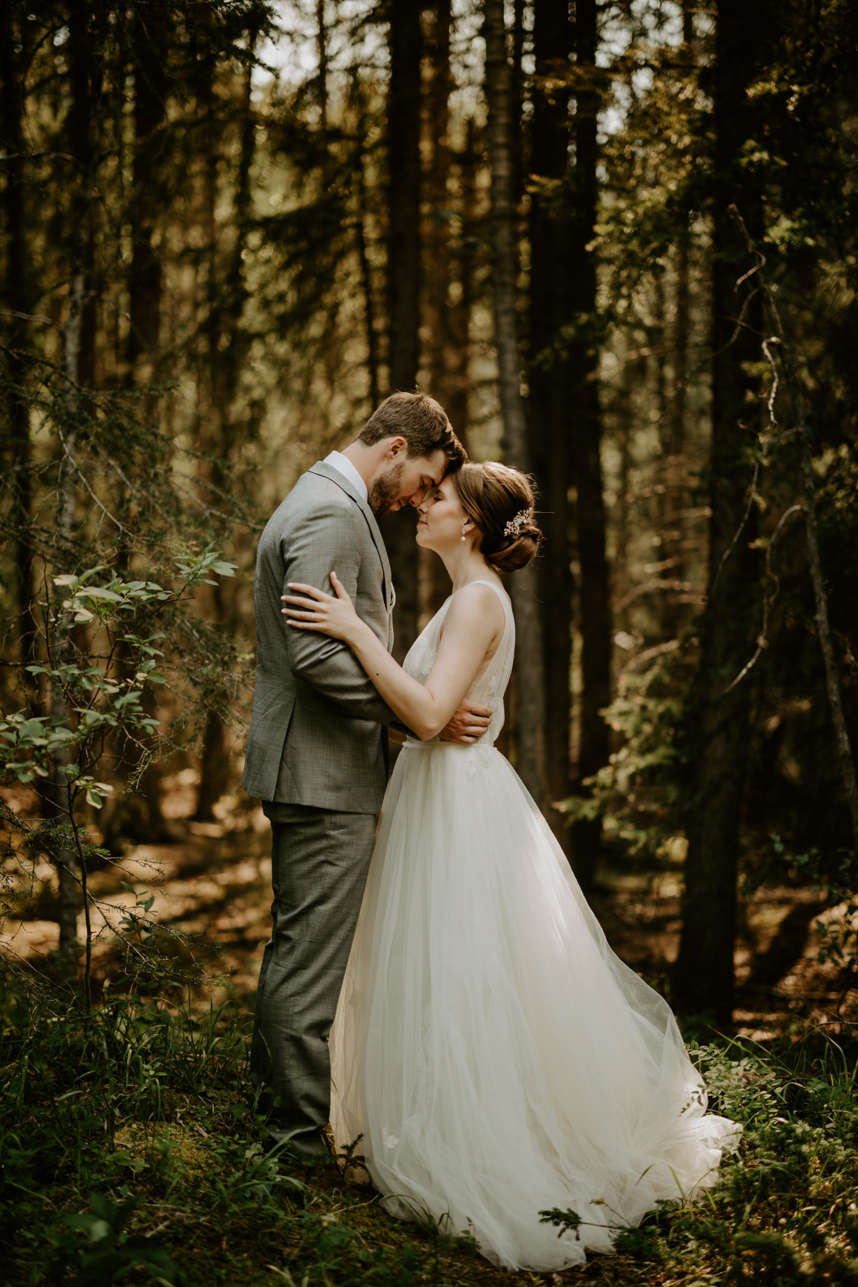 The Real Bride Couple, Laura and Braedon are embracing each other in a beautiful setting and Laura is wearing the Lainie gown by Willowby Bridal.